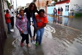 Lydia Cumming digendong dua ibu-ibu, korban banjir, saat liputan. (Foto: CEN)