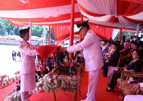 Gubernur Olly Dondokambey SE selaku Irup menyerahkan Sang Saka Merah Putih untuk dikibarkan kepada pembawa Baki Bendera