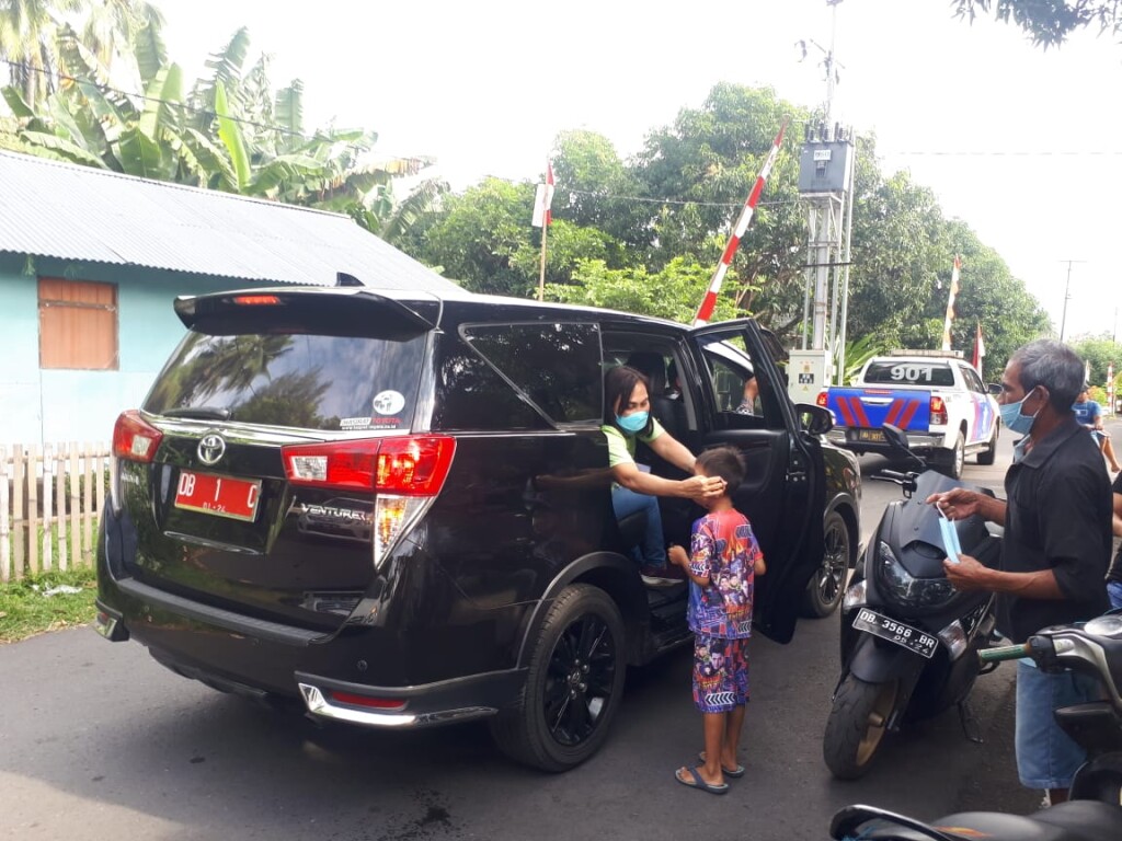 Dengan penuh Cinta, Ibu Khouni Lomban Rawung Kampanye memakaikan masker pada seorang anak