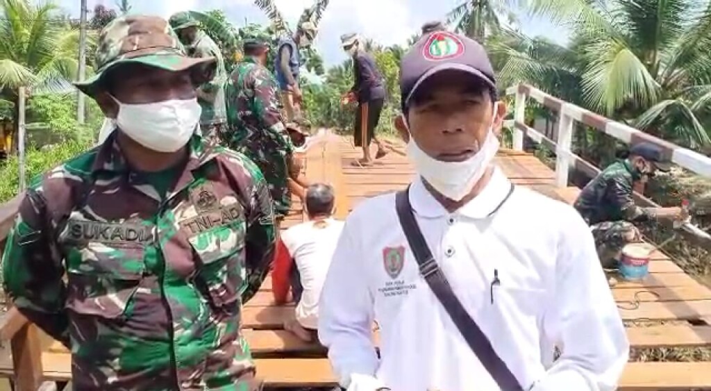 Kepala Desa Bapinang Hilir, Bahriansyah bersama Satgas TMMD Reguler ke-109 yang sedang merampungkan perbaikan jembatan.