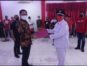 Bupati Joune Ganda menyerahkan SK Penjabat Kumtua Desa Wori kepada Rommy Charles Lopo.