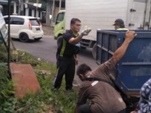 Penjabat Kumtua Mapanget Gerald Kalesaran tampak mengangkut sampah di pinggir jalan.